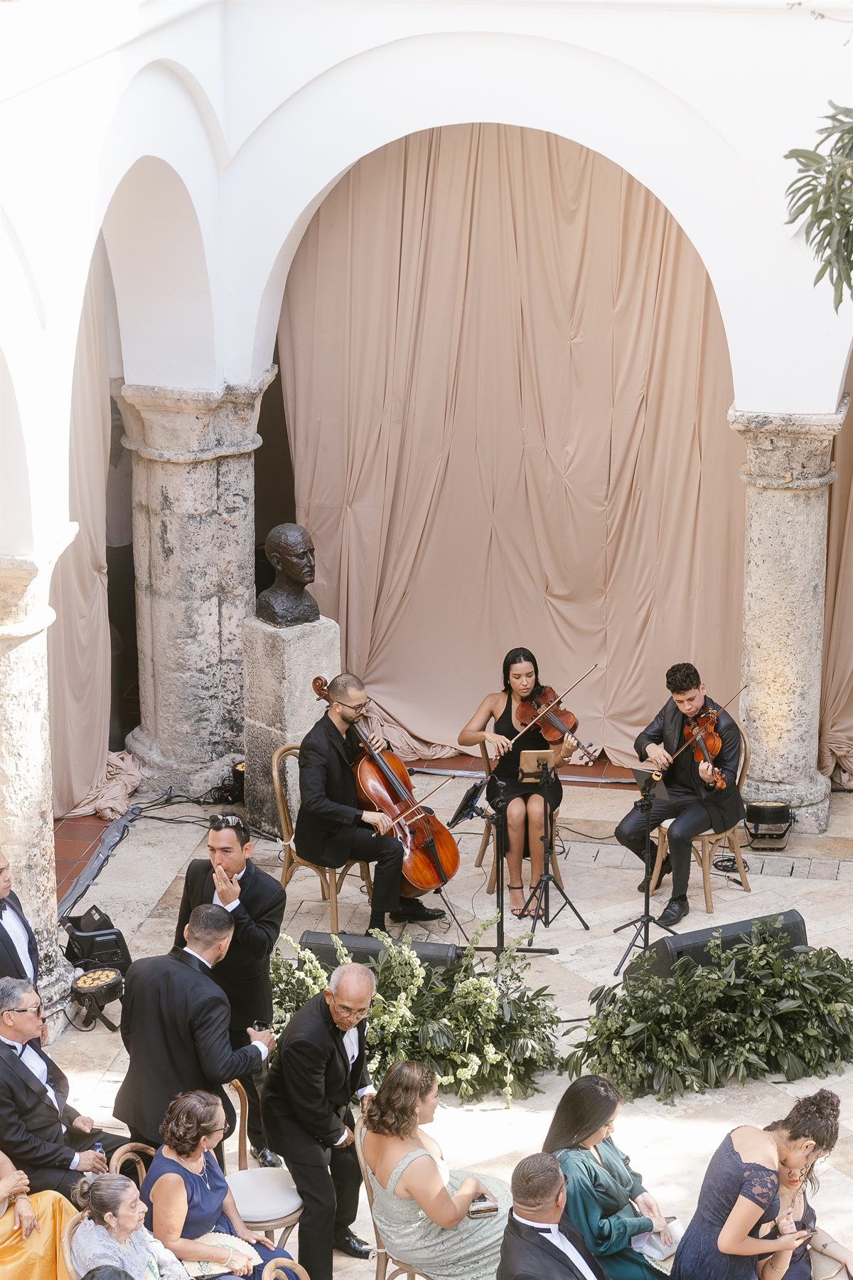 Trío de cuerdas de 3 Cuerdas Music durante una ceremonia de boda en un patio colonial de Cartagena, con los invitados